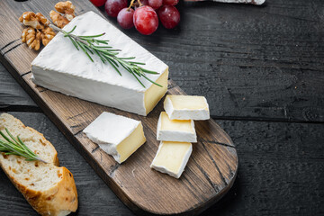 Delicious brie cheese, on black wooden table  with copy space for text - obrazy, fototapety, plakaty