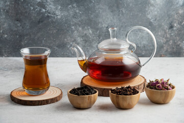 A glass teapot with tea on a wooden board
