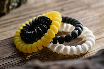 Fashionable and modern elastic hair springs. Different colors of stretching hand bracelets on wooden background, stand
