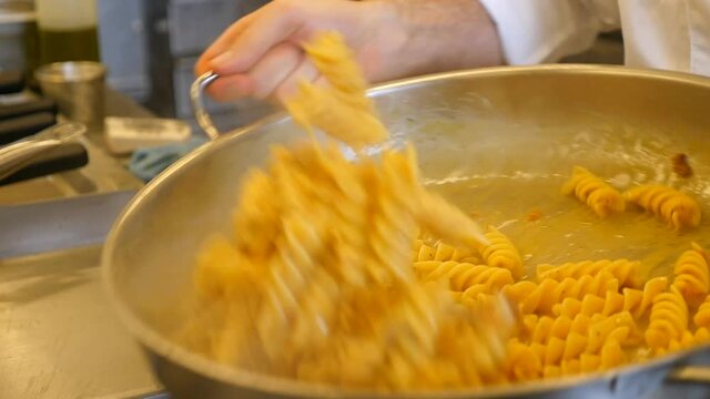lo chef mescola la pasta facendola saltare in padella. poi la versa nel piatti e aggiunge del formaggio.
Tre scene in cui lo chef prepara un piatto gourmet. 