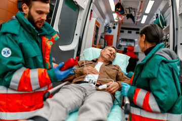 Paramedics check the level of oxygen in the blood and transport the elderly patient's gurney from...