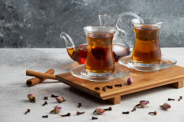 Two glass cups of tea with cinnamon sticks and dried roses