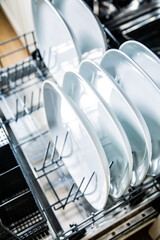 White plates in an open dishwasher, top view, close-up.