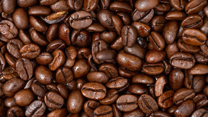 Fullframe shot of fresh roastend coffee beans zoom in. Aromatic brown textured seeds on background from close up. Black energy structured grain on backdrop.