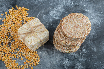 Two types of crispbread and raw corn seeds on marble background
