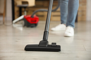 Young man using vacuum cleaner at home, closeup