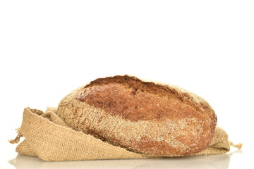 One loaf of freshly baked buckwheat bread on a jute bag, close-up, isolated on white.