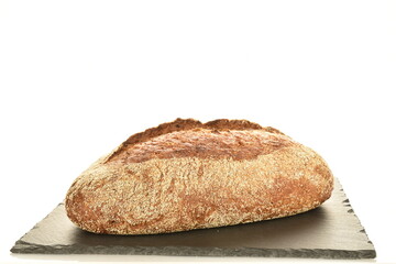 One loaf of freshly baked buckwheat bread on a slate board, close-up, isolated on white.