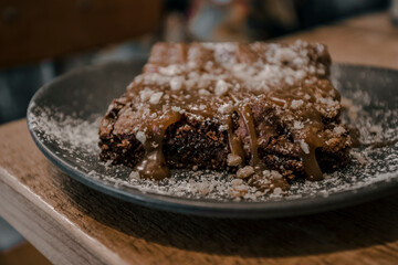 Plate with slice of tasty homemade chocolate cake on wooden table. Homemade brownie cake