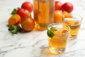 Delicious plum liquor with mint on white table. Homemade strong alcoholic beverage