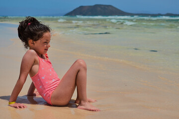 Girl sitting on the shore of the beach looking at the sea