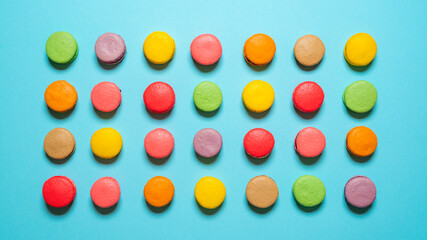 Homemade macarons flat lay. Multicolored macaroons top view on blue background