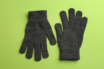 Pair of stylish woolen gloves on green background, flat lay