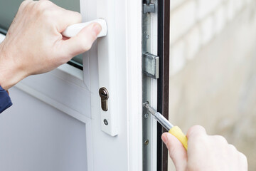 Handyman installing lock in plastic front door. Checking the lock for operability and strength.