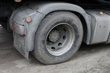 one big gray dirty wheel of a truck on the street on the asphalt road