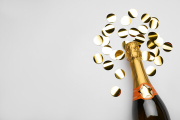 Flat lay composition with confetti and bottle of champagne on light background. Space for text