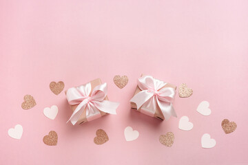 Gift boxes with pink ribbon and hearts on pastel pink background. Valentines day composition with free space. Top view, flat lay.