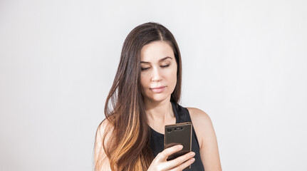 Fototapeta premium Young Brunnete looks in the phone. White background
