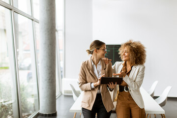 Women holding digital tablet and working in modern office