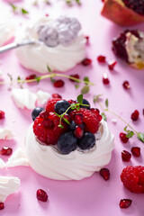 Pavlova meringue cake with cream and berries on dusted sugar pink background