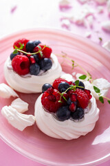 Pavlova meringue cake with cream and berries on dusted sugar pink background