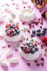 Pavlova meringue cake with cream and berries on dusted sugar pink background