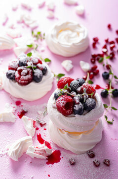 Pavlova meringue cake with cream and berries on dusted sugar pink background