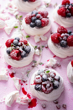 Pavlova meringue cake with cream and berries on dusted sugar pink background