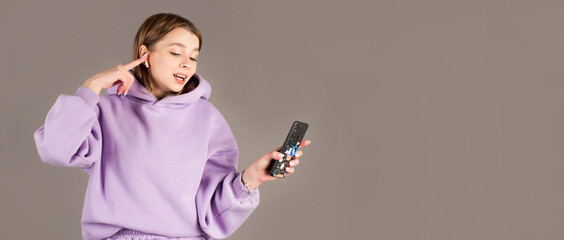 Image of a happy young beautiful woman posing isolated over gray wall background listening music with earphones using mobile phone.