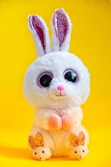 Cute easter bunny rabbit plush doll sitting on yellow background.