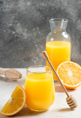 A glass cup of fresh orange juice with a wooden dipper
