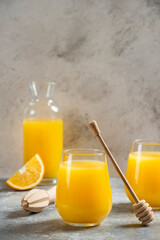 A glass cups of orange juice and a wooden dipper
