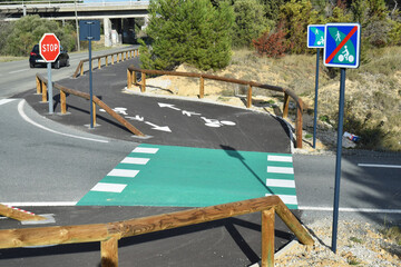 Piste cyclable avec passage d'une route matérialisée en vert.