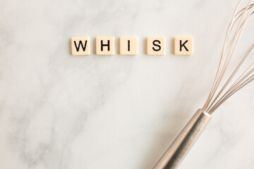 scrabble tiles on the marble countertop spelling the word whisk