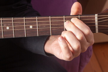 Fototapeta na wymiar Close up on the hand of a man playing on the fretboard of an acoustic guitar