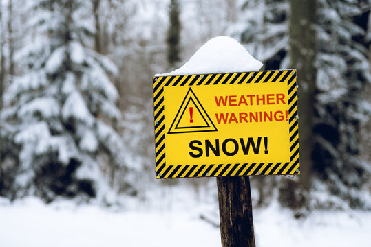 Yellow Weather Warning Snow Sign In The Out Of Focus Forest Background