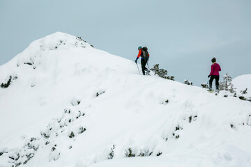 Fototapeta na wymiar Two hikers alpinist climbing up the snowy mountain on Sunset. Alpine winter view. Carpathians, Marmarosy