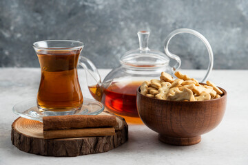 A glass cup of tea with wooden bowl full of crackers