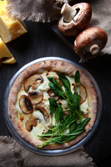 Pizza with royal mushrooms and spinach. Italian pizza. Metal plate for serving. Young spinach. Vertical photo. View from above.