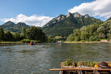 Tourists rafting and punting in beautiful summer weather on the Dunajec River on the border between Poland and Slovakia with Trzy Korony Mountain in Pieniny National Park in the background  © QuiBee