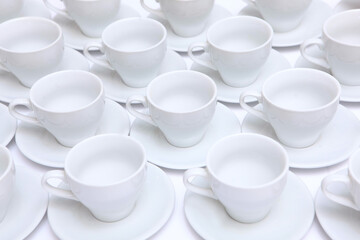 A large number of white porcelain or ceramic tea pairs on the table. Catering or banquet concept. View from above.