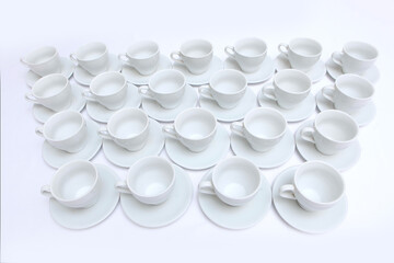 A large amount of white porcelain or ceramic crockery on the table. Tea pairs in abundance. Dishes for tea drinking. Catering or banquet concept. View from above.