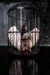 girl with angel wings kneels in a cage © Дмитрий Хитрин