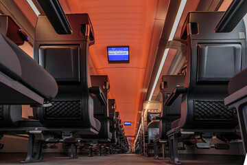 First class railroad car on German railways. Central view in the hallway with carpeted floor. Empty seats with no passengers while driving. Digital display boards in the train compartment
