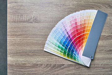 Color wheel palette for choosing paint tone. Various colors on wooden table background with copy space. Interior designer tool.