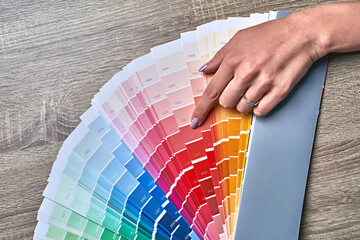 Color wheel for choosing paint tone. Hands of female interior designer working with palette for...