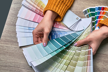 Color wheel for choosing paint tone. Hands of female interior designer working with palette for...