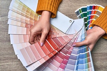 Color wheel for choosing paint tone. Hands of female interior designer working with palette for...
