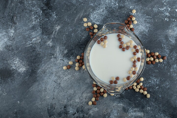 Fototapeta na wymiar Sweet cereal balls and bowl of milk on marble background