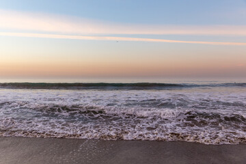 Waves washing ashore in colorful sunrise at Malibu Beach, California